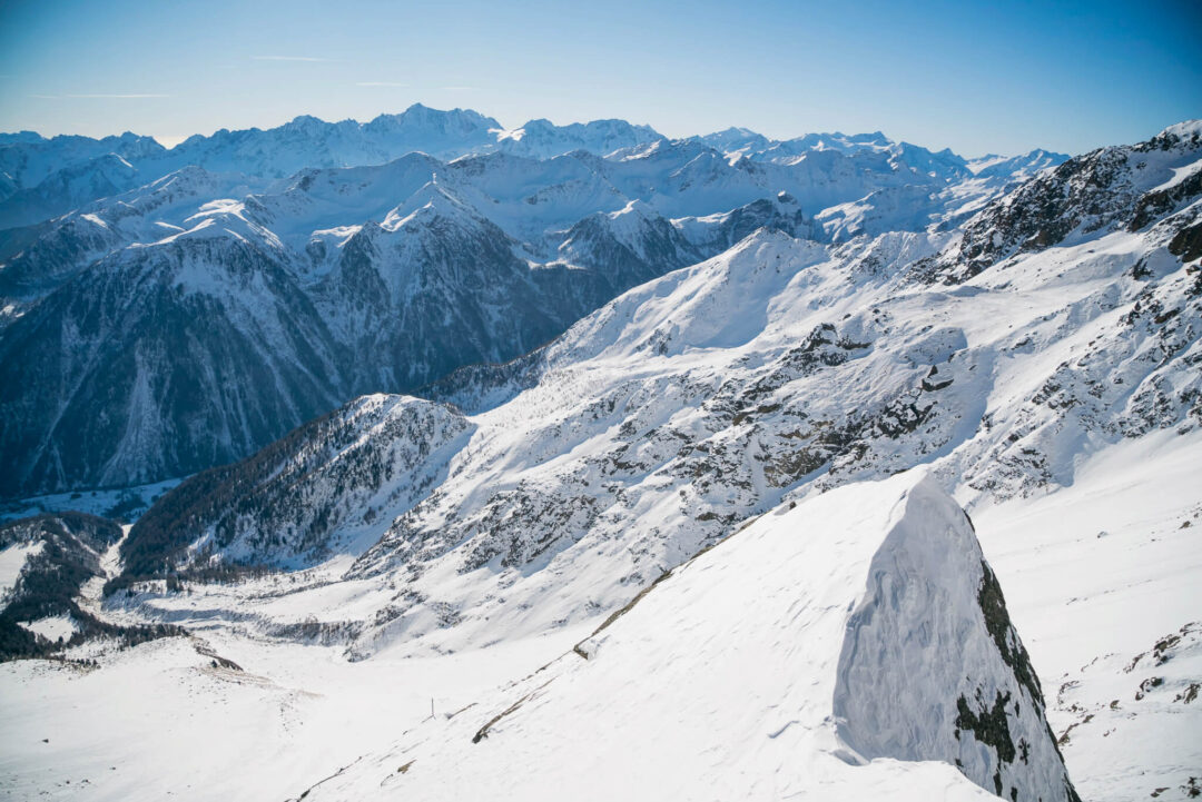 Snowshoe tracks across a snowy Dolomites mountain ridge with panoramic peaks in bright winter sunshine