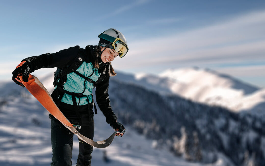 Ski touring skier in helmet and goggles climbing a snowy mountain ridge at sunrise in Sweden
