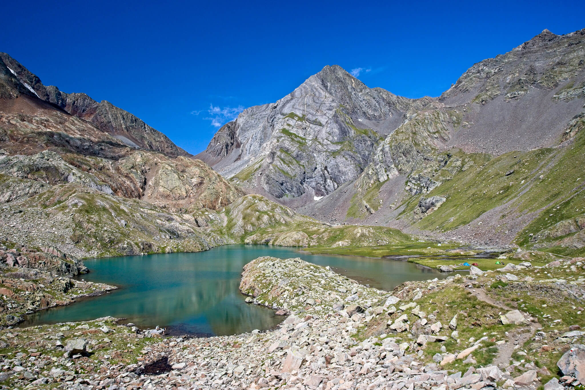 Alpine lake in rugged mountains, scenic hiking landscape under a clear blue sky