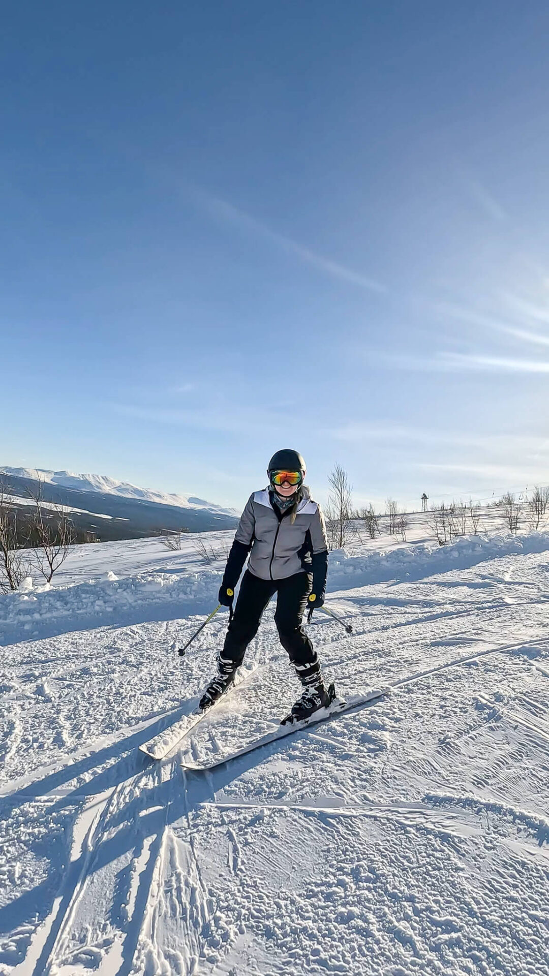Beginner skier carving a run on a groomed snowy slope in Sweden’s mountains under clear skies