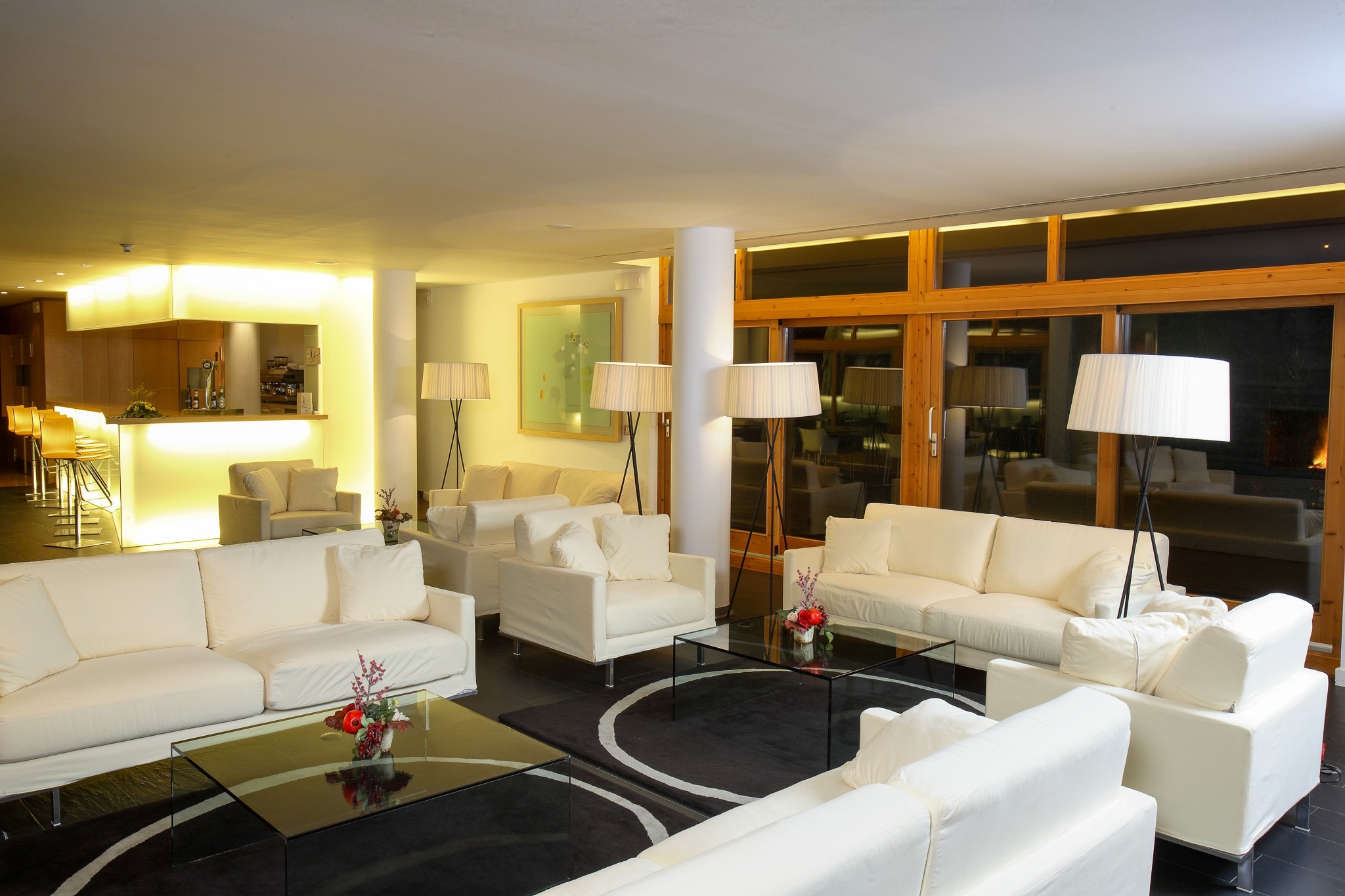 Modern hotel lounge with white sofas, coffee tables and large windows with balcony doors
