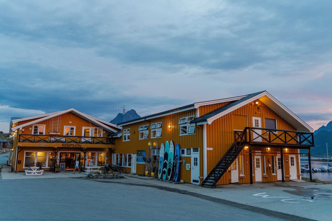 SUP and kayak boards outside a wooden waterfront building in Lofoten, Norway at dusk