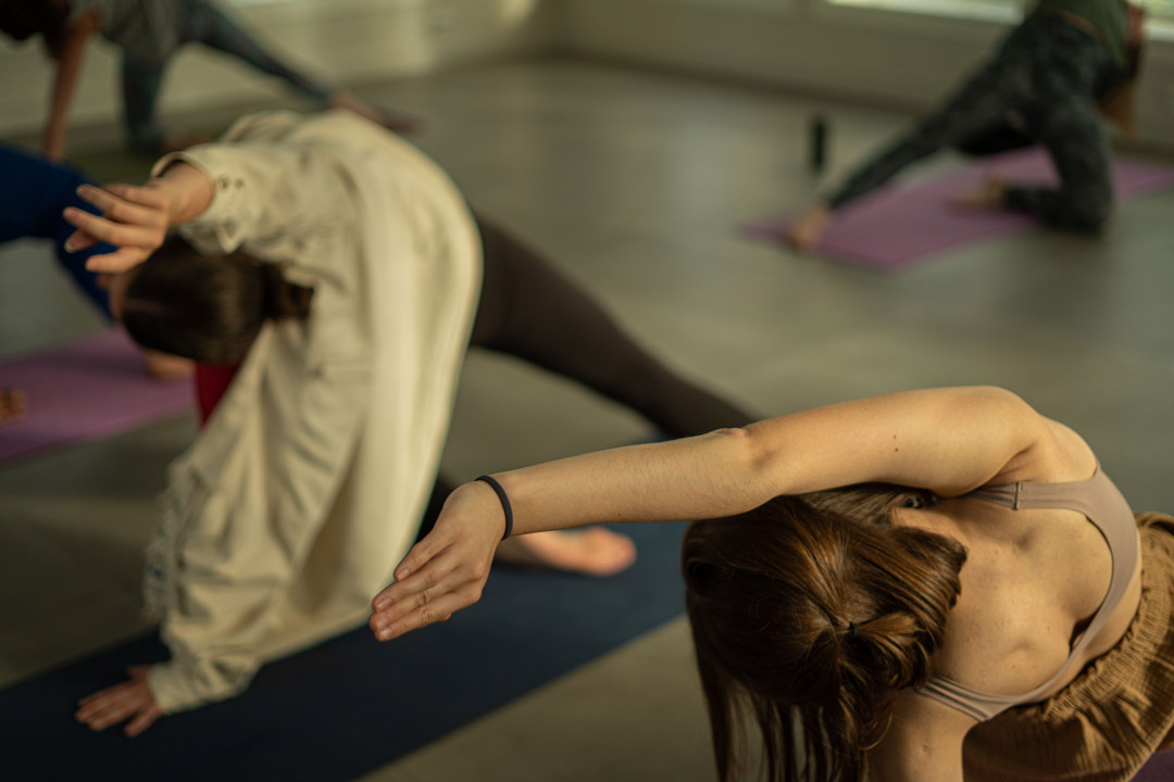 Women stretching on yoga mats during an adventure holiday briefing indoors