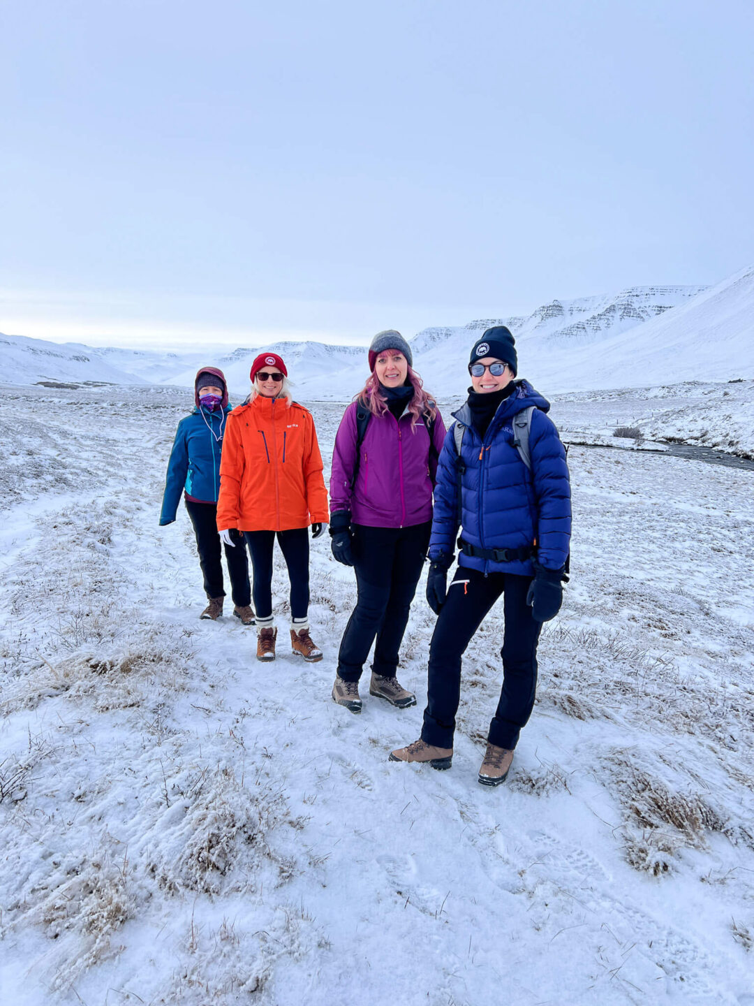 Group of winter hikers posing in snowy North Iceland mountains under a clear blue sky