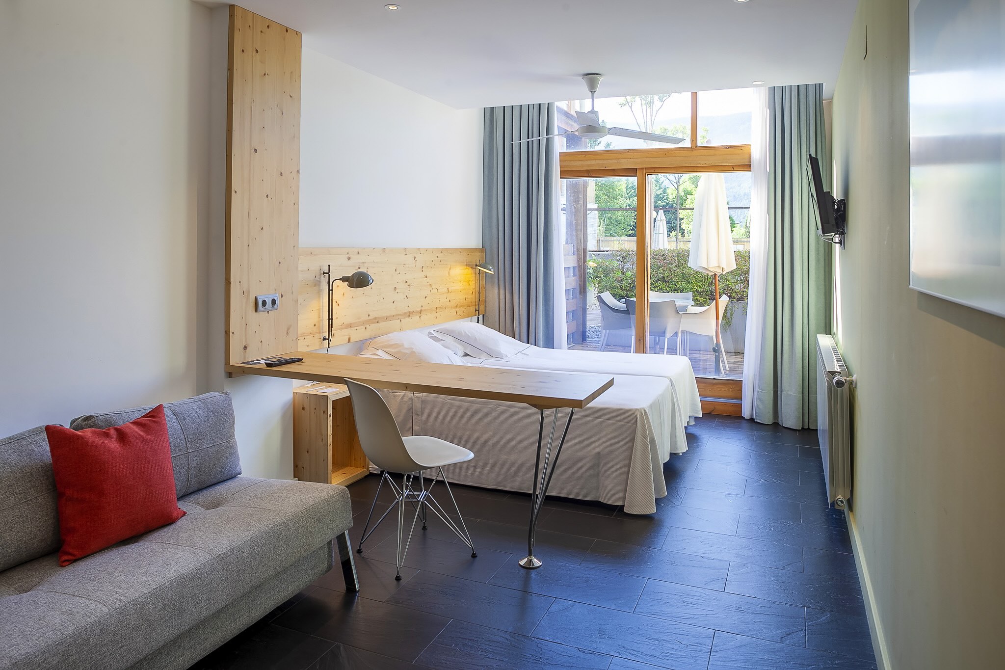 Hotel room interior with double bed, sofa seating and balcony doors overlooking the garden