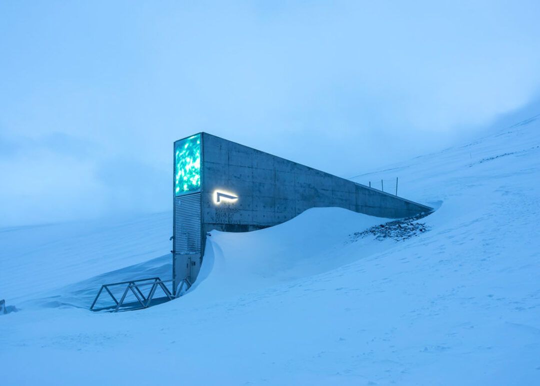 Snowy mountain ski lift station building with glowing green light at dawn, in a cold alpine landscape