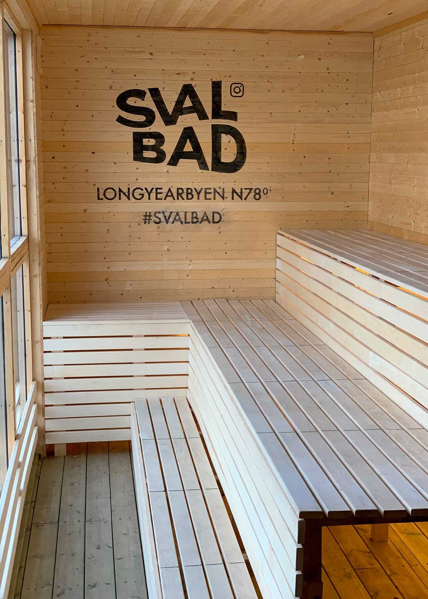 Sauna interior with wall text “SVAL BAD”, “LONGYEARBYEN N78°” and “#SVALBAD”