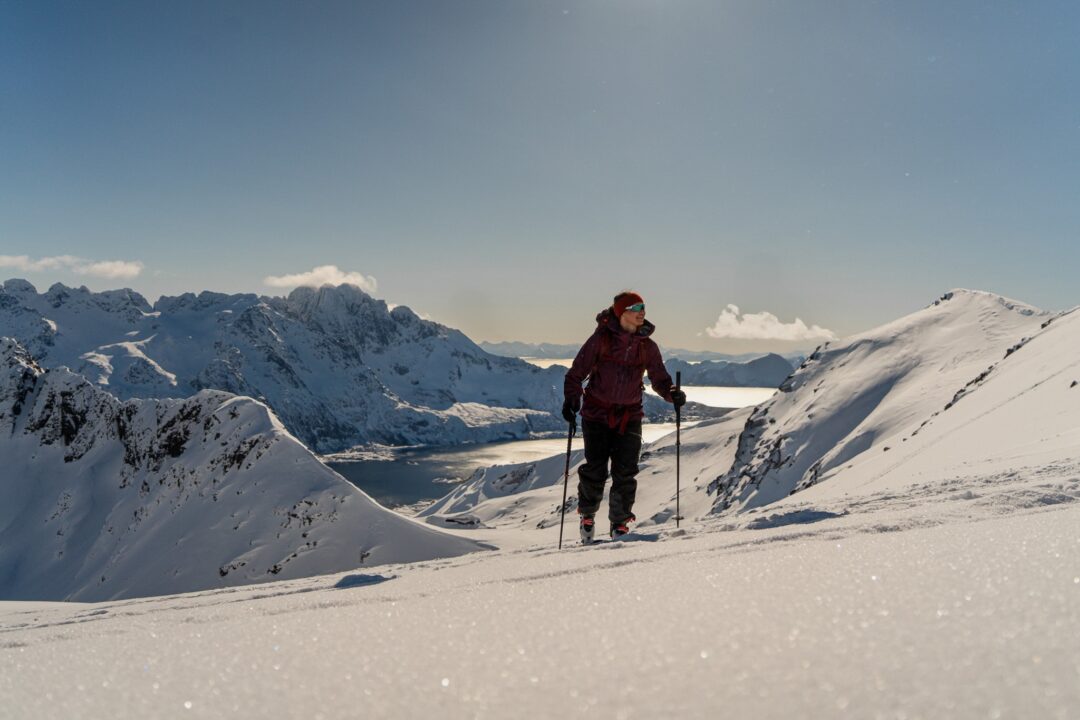 Skier on snowy Lofoten mountains with dramatic fjord peaks at sunset