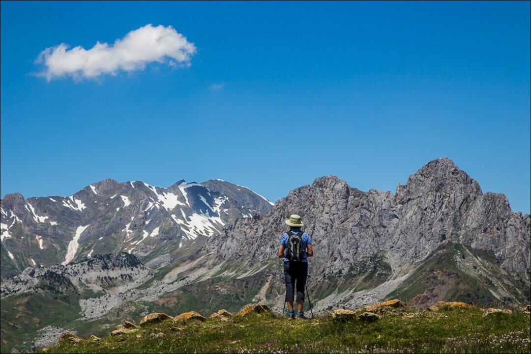 Hiker walking along a mountain ridge in the Spanish Pyrenees under a clear blue sky