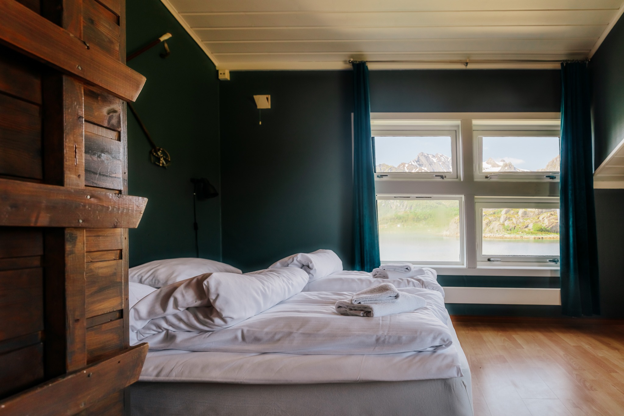 Cozy bedroom with bed and large windows overlooking Lofoten mountains and water, ready for a winter adventure.