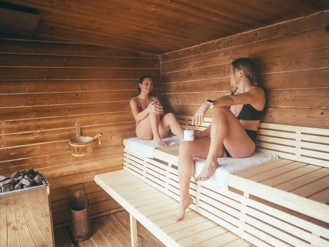 Women relaxing in a wooden sauna, warm steam room interior for a Lofoten adventure holiday