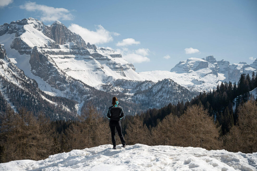 Snowy viewpoint in the Dolomites with a hiker standing on fresh snow above Alpine valleys