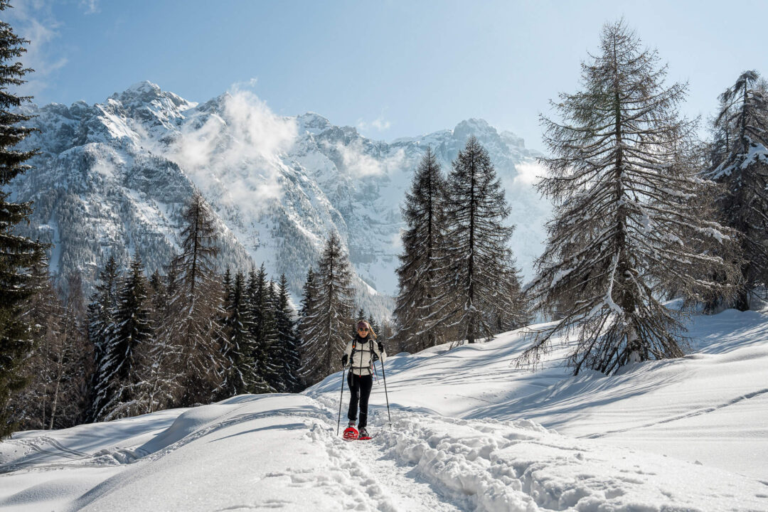 Guided snowshoe trek in snowy Dolomite mountains with hikers on a mountain path