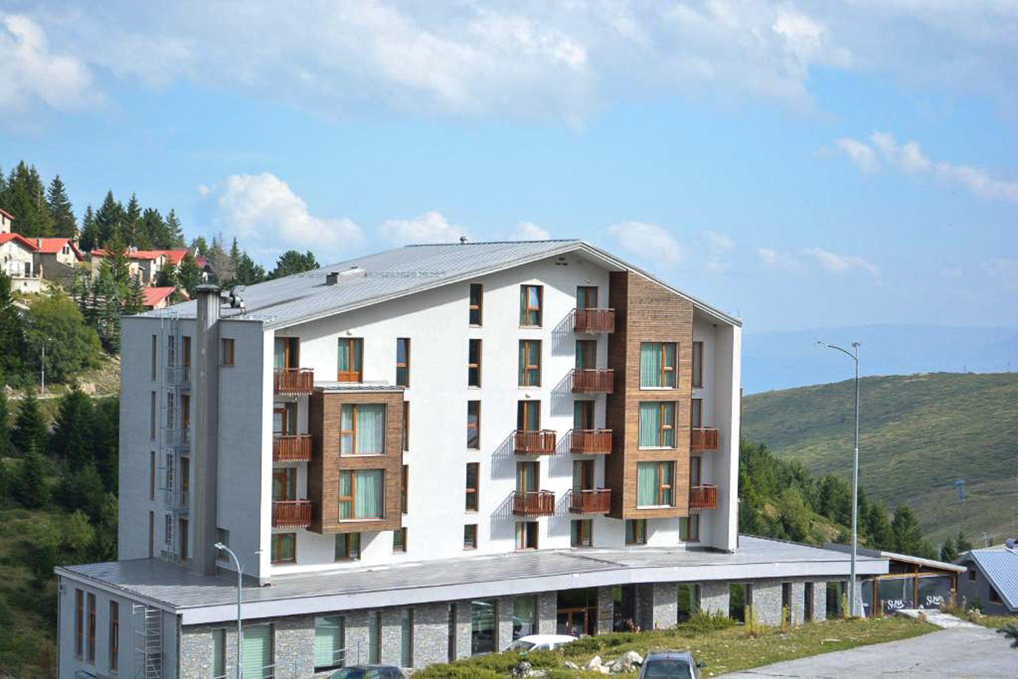Modern hotel exterior with balconies overlooking a green hillside landscape, in North Macedonia