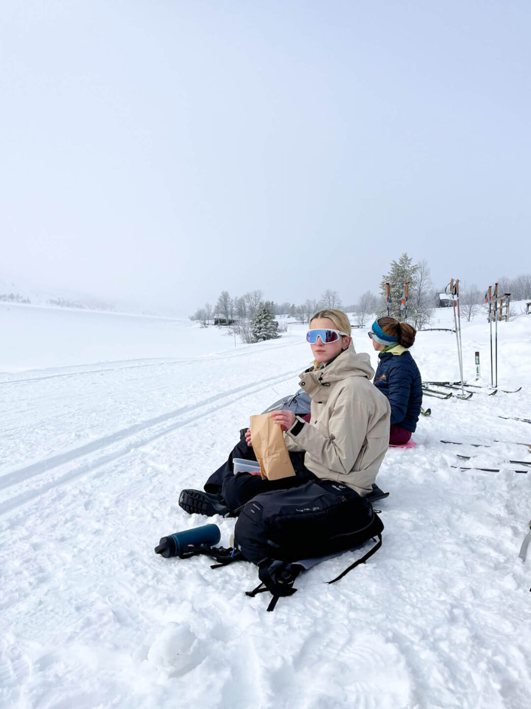 Beginners on cross-country skis resting on snow at a snowy Norwegian ski trail, winter training day outdoors