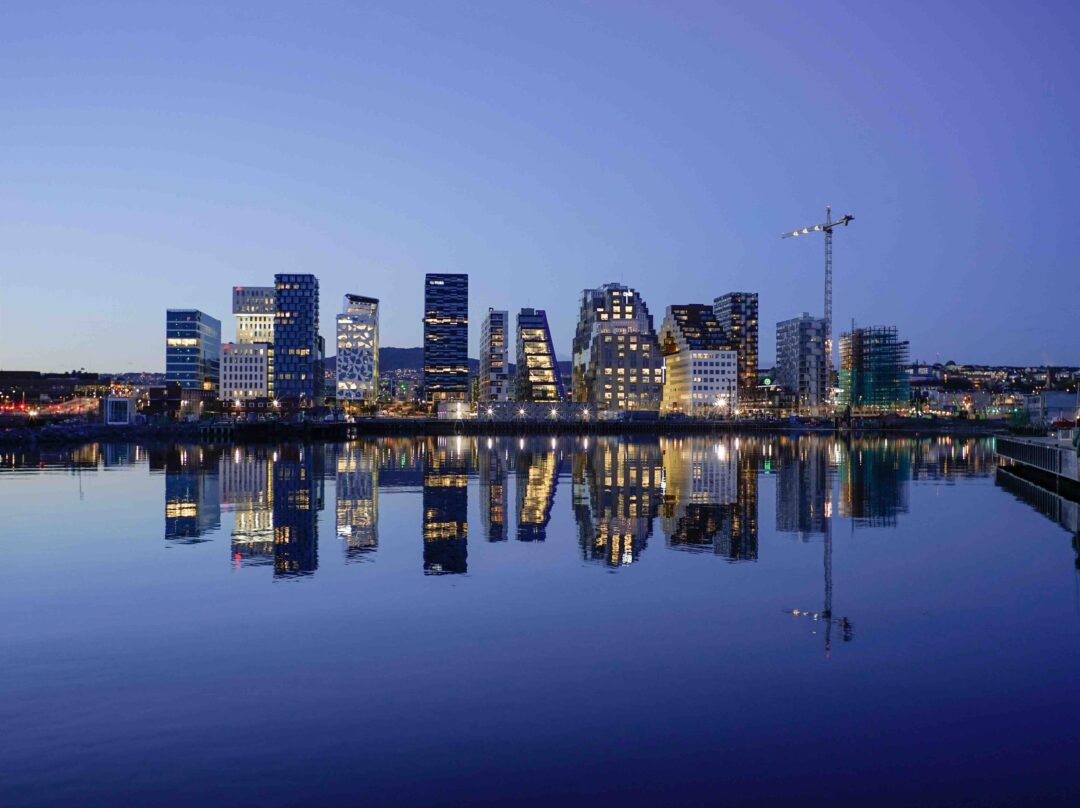 Oslo city skyline at dusk with illuminated buildings reflected in the calm river, Norway