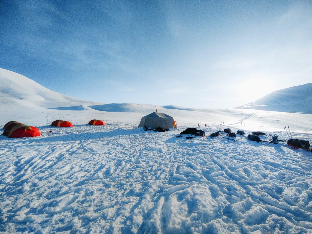 Snow camping tent and sleeping bags in a snowy Arctic landscape for a winter wild camping expedition