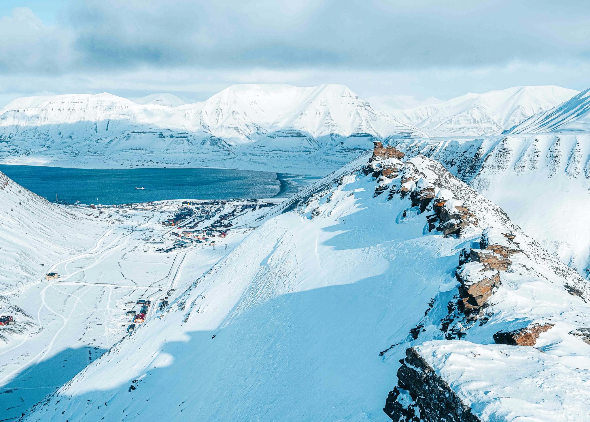 Snowshoe tracks on a snow-covered mountain ridge in Svalbard with Arctic glaciers in the distance