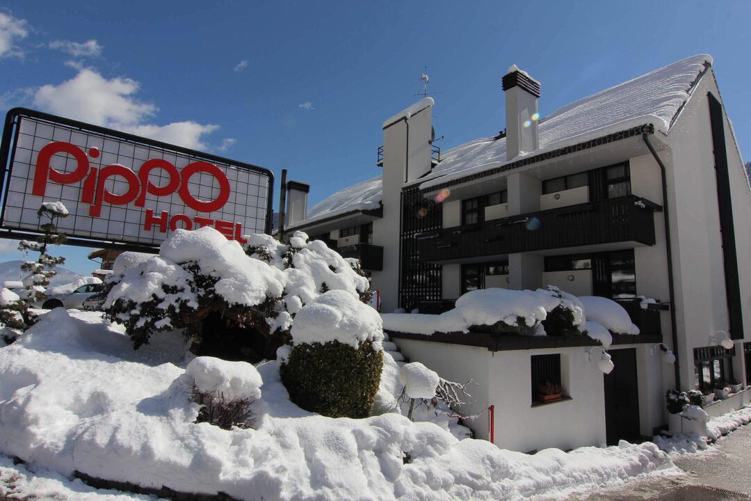 Snowy Dolomites chalet with red “pioppo” sign outside a modern lodge building in winter