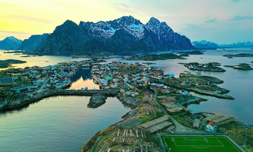 Aerial view of a Lofoten fishing village beside fjords and mountains along the coastline