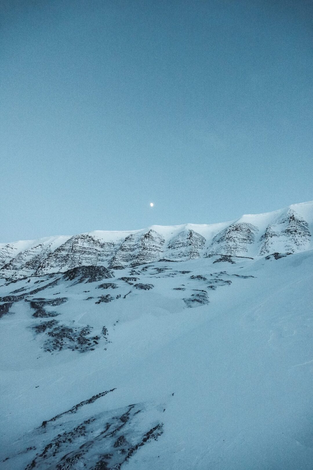 Snowy Svalbard mountains under a clear blue sky, arctic winter landscape