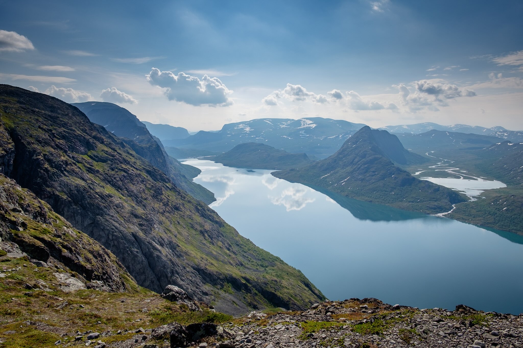 Norwegian mountain hiking viewpoint overlooking fjords and a turquoise bay under dramatic clouds