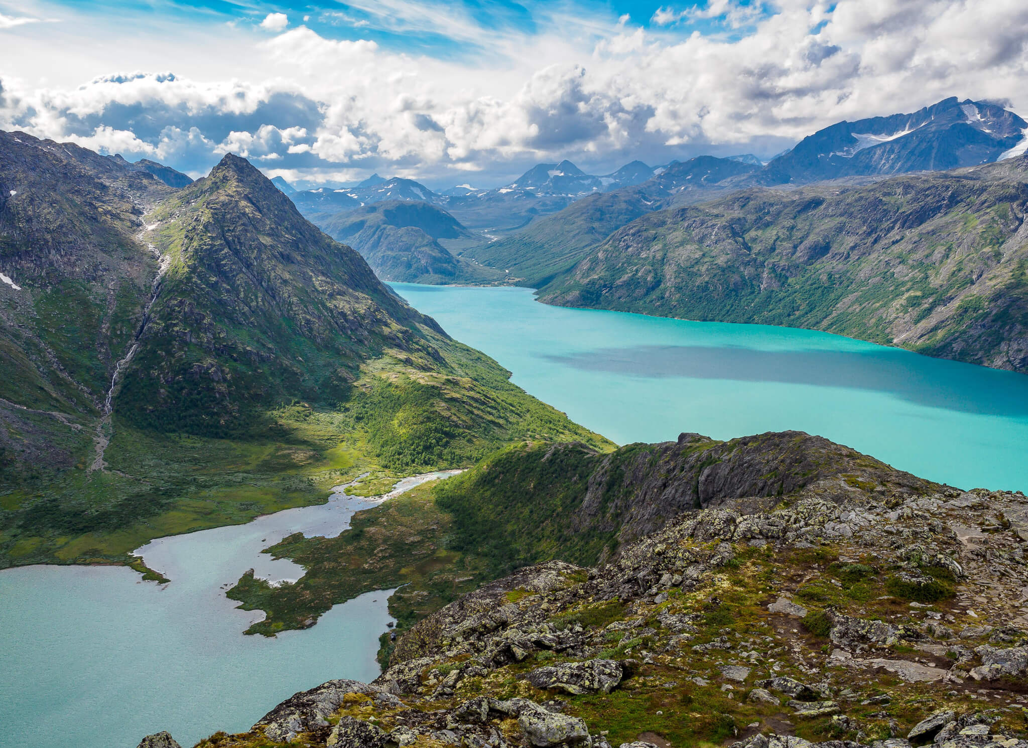 Panoramic view from a mountainside hiking trail over Norway’s turquoise fjord and peaks in the summer