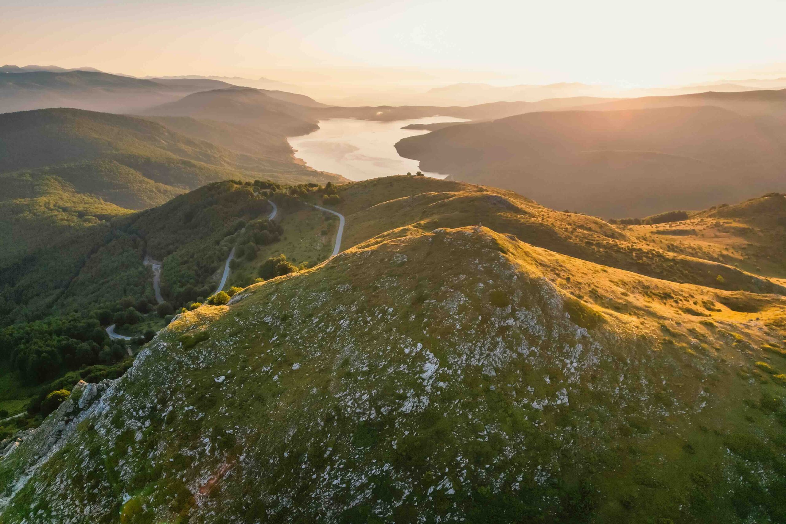 Winding mountain road over a valley with a river at sunrise in North Macedonia’s national parks