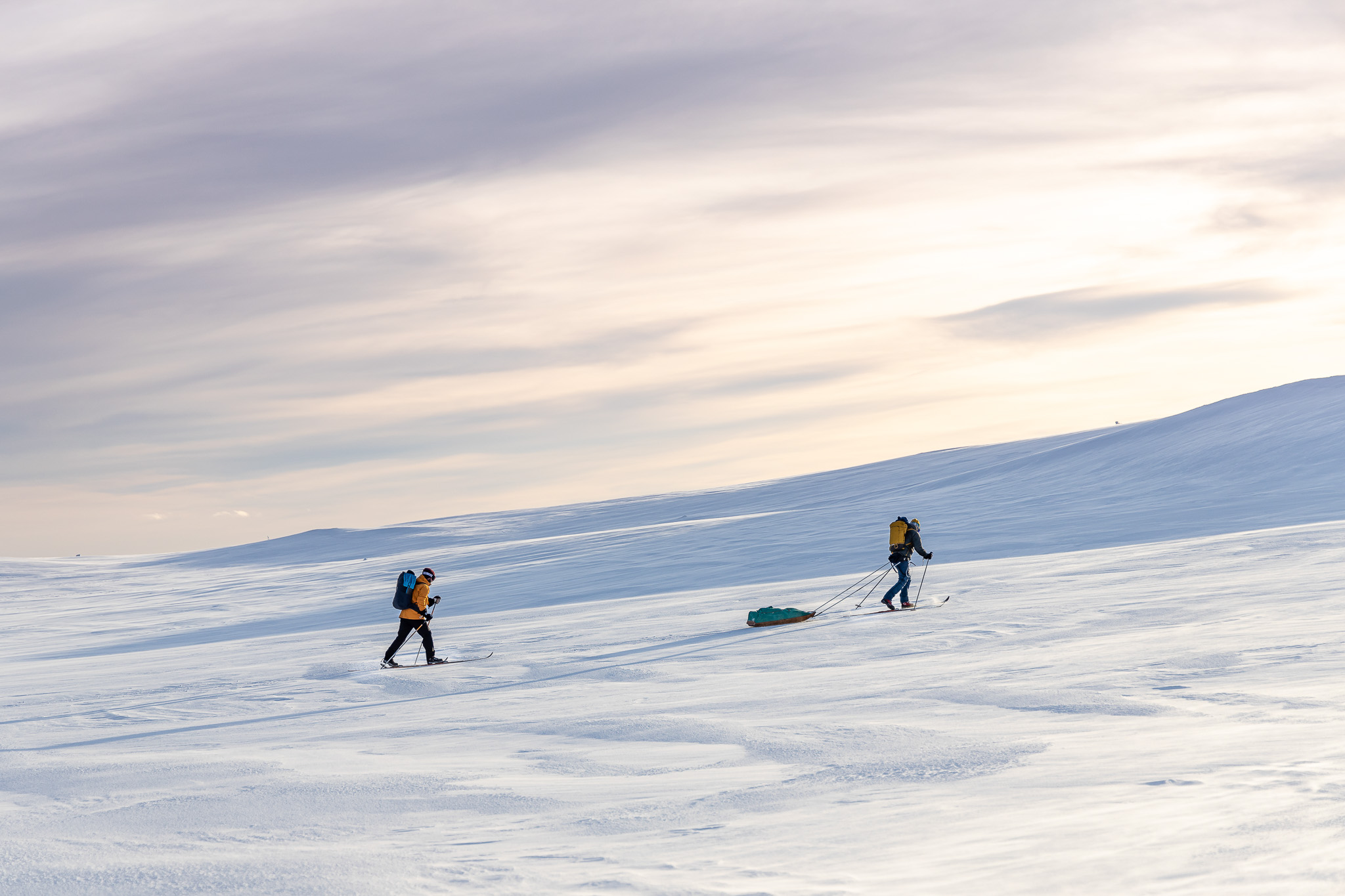 Snowboarders riding a snowy mountain slope at sunset