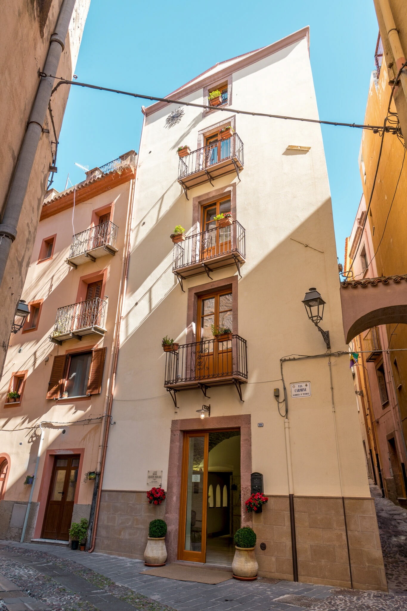 Narrow street with white Mediterranean apartment buildings and balconies under a clear blue sky in Sardinia