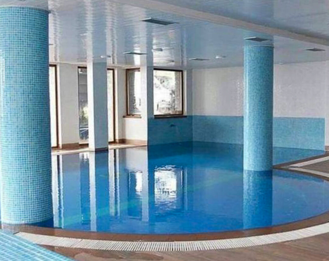 Indoor swimming pool with blue-tiled walls and pillars in a spa setting