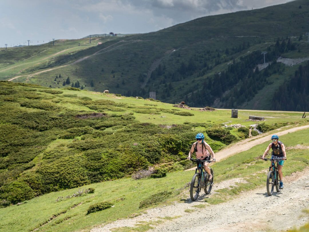 Women e-biking on a gravel track through green hills and forest in North Macedonia’s national park landscape
