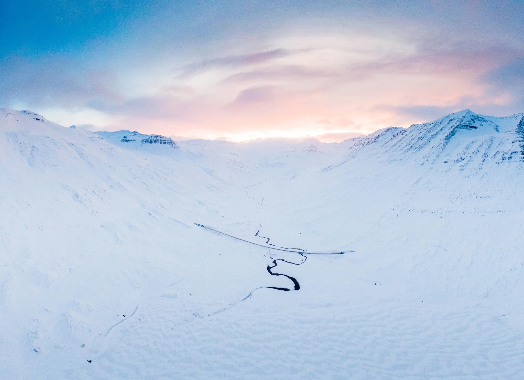Snowy mountain ski slope with downhill tracks at sunrise in a winter alpine landscape