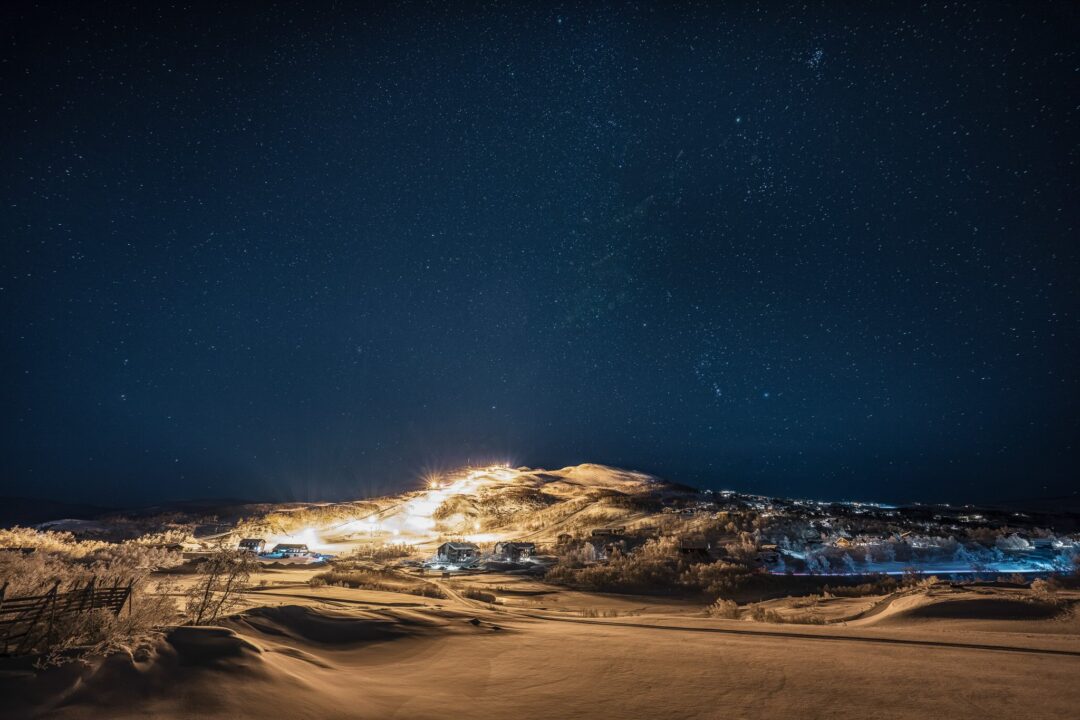 Snowy cross-country ski trail at night under a starry sky
