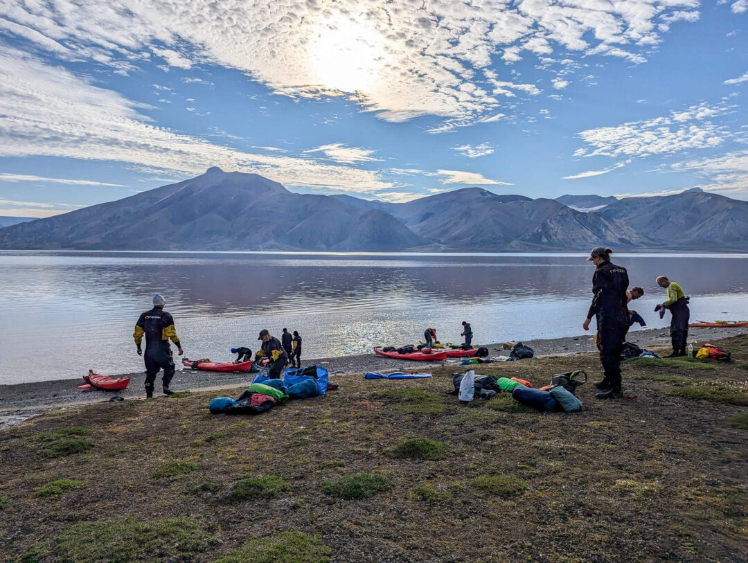 Kayaks and expedition gear on a shore during an Arctic summer kayaking trip in Svalbard
