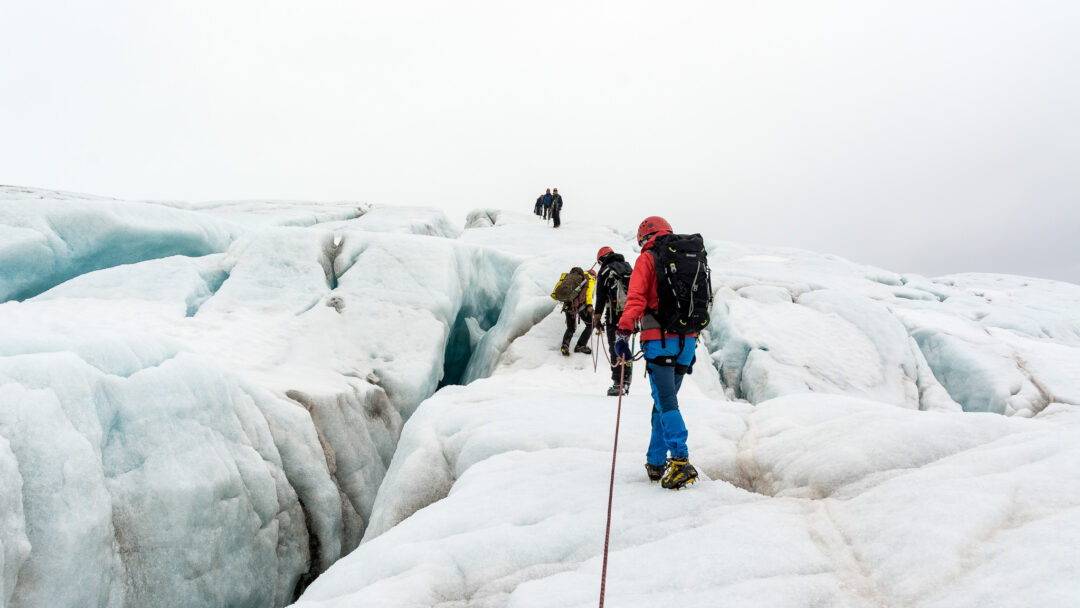 Hikers trekking across a glacier in Arctic wilderness during summer expedition