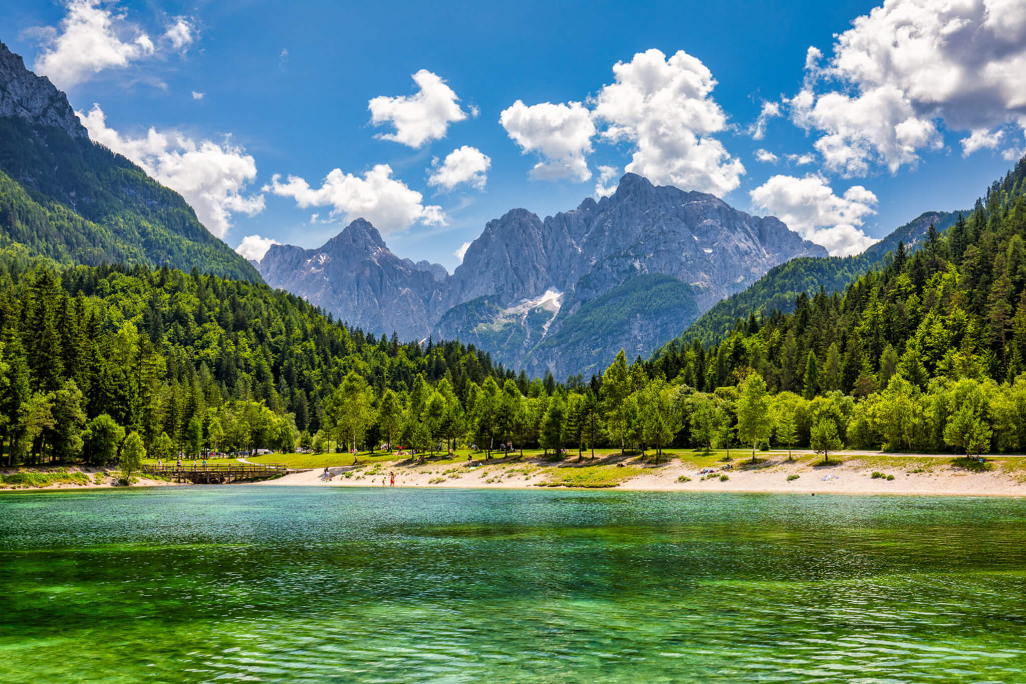 Scenic lake and alpine peaks in Slovenia, surrounded by dense green forests and valley slopes