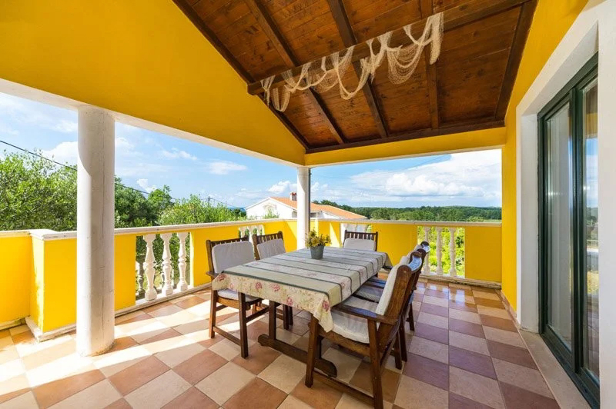 Sunny seaside terrace with dining table and chairs overlooking the water in Croatia