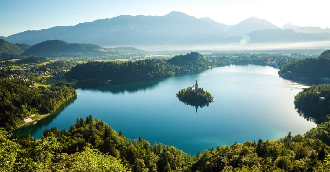 Misty mountain lake with forested banks and small island in the water