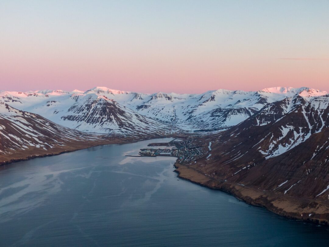 Snowy mountains and calm fjord at dusk in North Iceland, seen from above