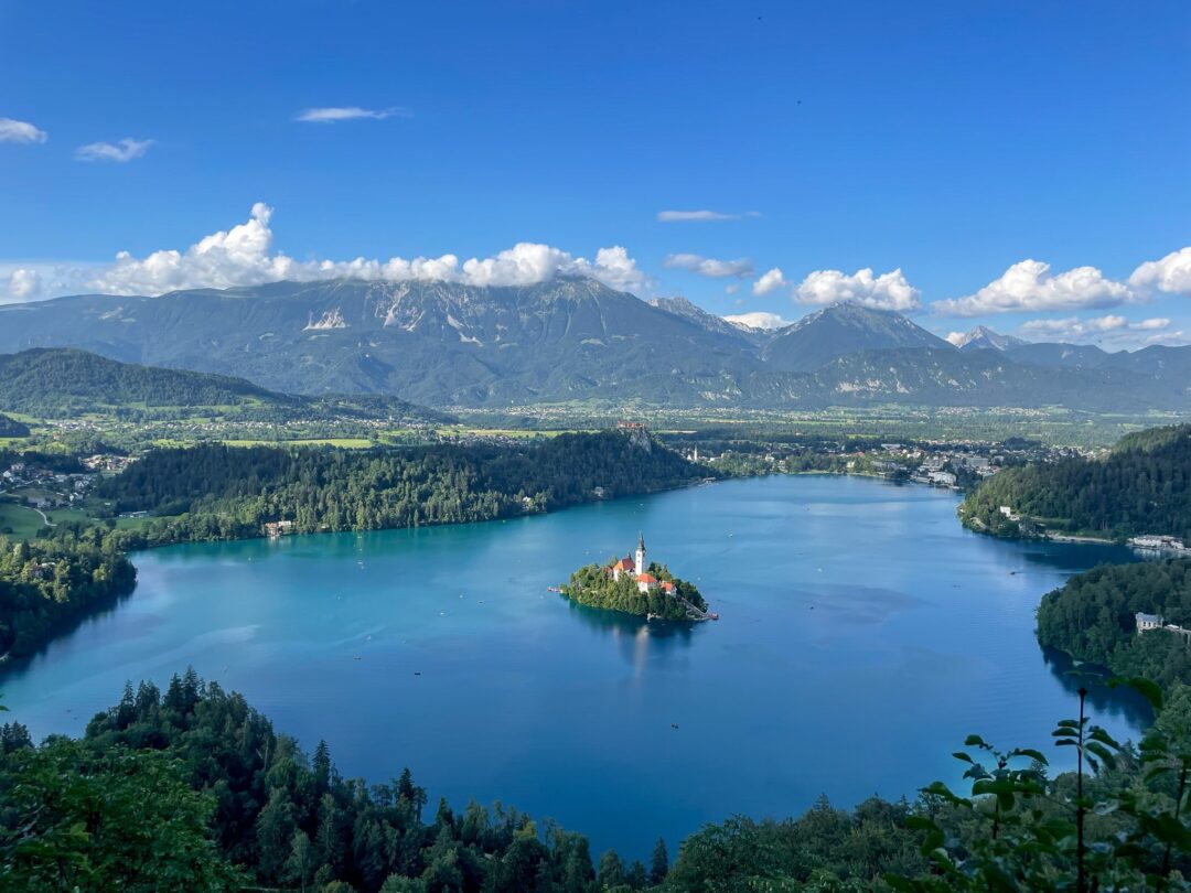 View over Slovenia’s Lake Bled with an island church and surrounding mountains, for hut-to-hut hiking adventure.