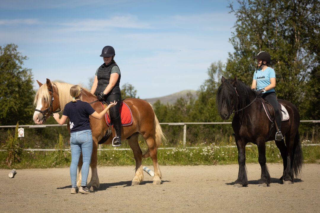 Women leading and mounting horses during an outdoor horse riding lesson