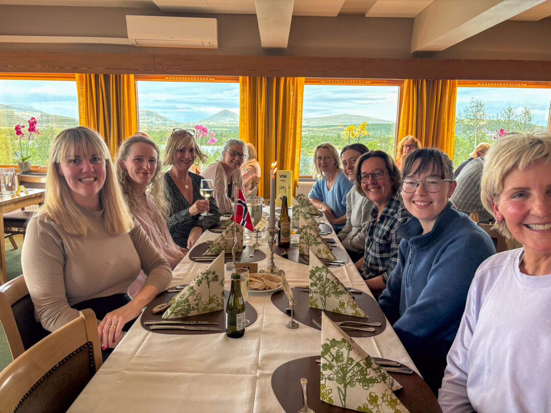 Women dining together in a restaurant with large windows showing a mountainous Norwegian landscape