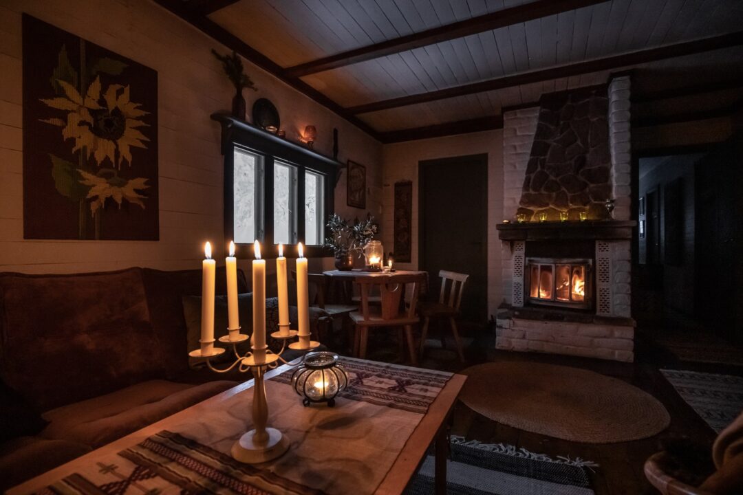 Cozy winter cabin interior with five candles and a stone fireplace, suitable for camping in Sweden