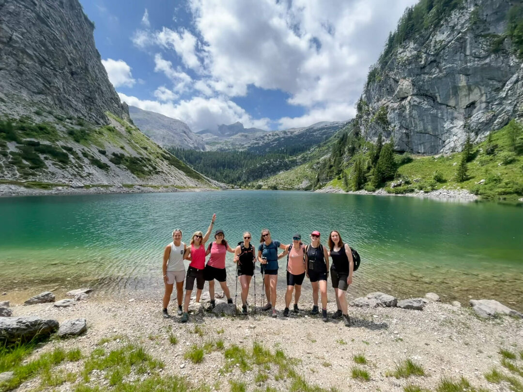 Women hikers standing by turquoise alpine lake in a mountain valley