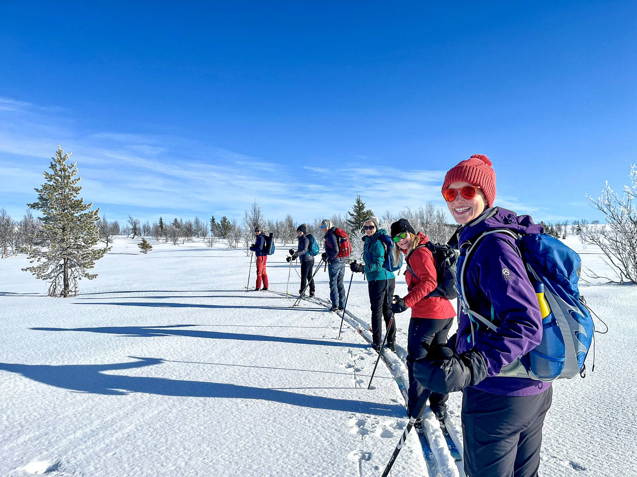 Women cross-country skiing on a snowy winter landscape under a blue sky
