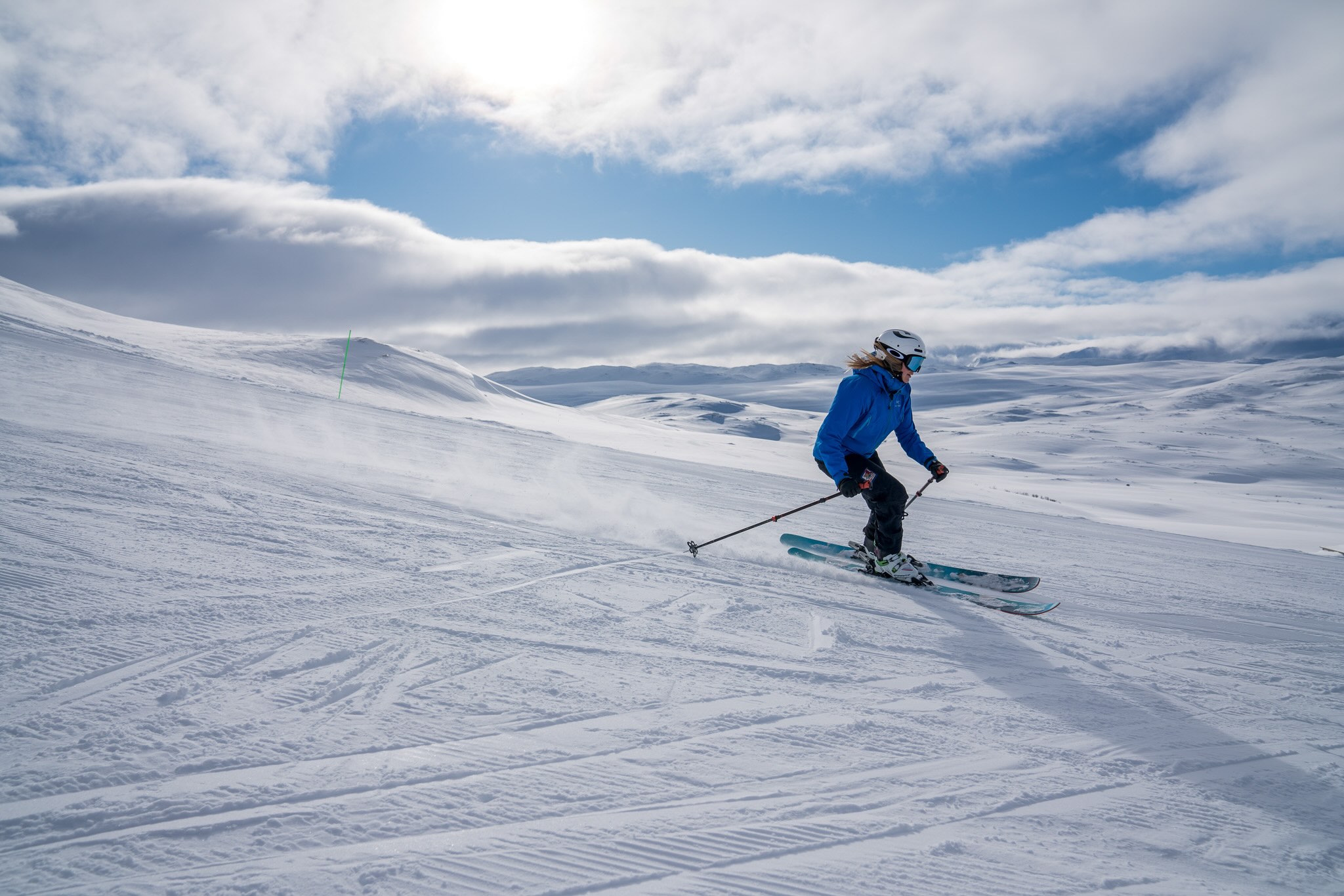 Woman skiing across snow-covered slopes under a cloudy sky