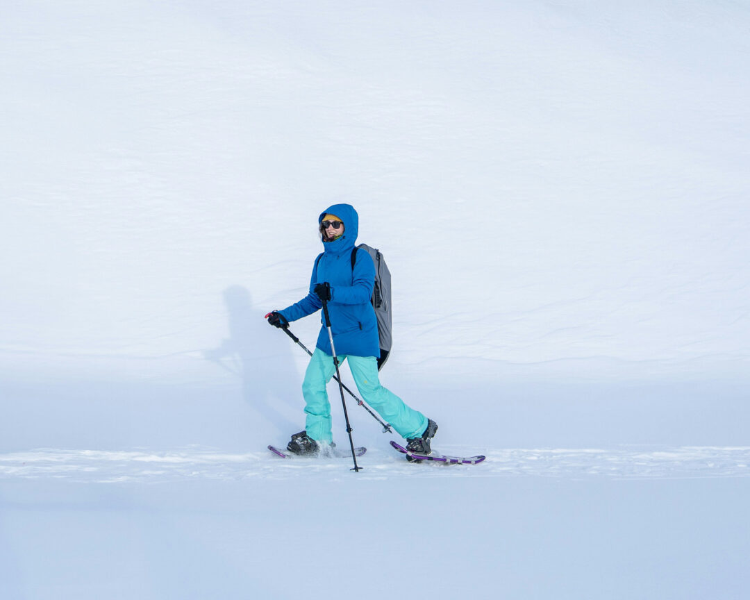 woman snowshoeing in bright blue clothes surrounded by snow