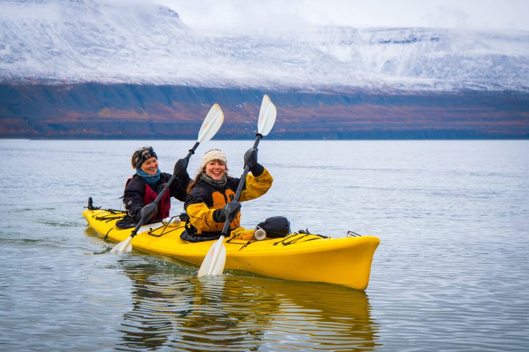 Women kayaking on Arctic sea in Svalbard with glacier in the background