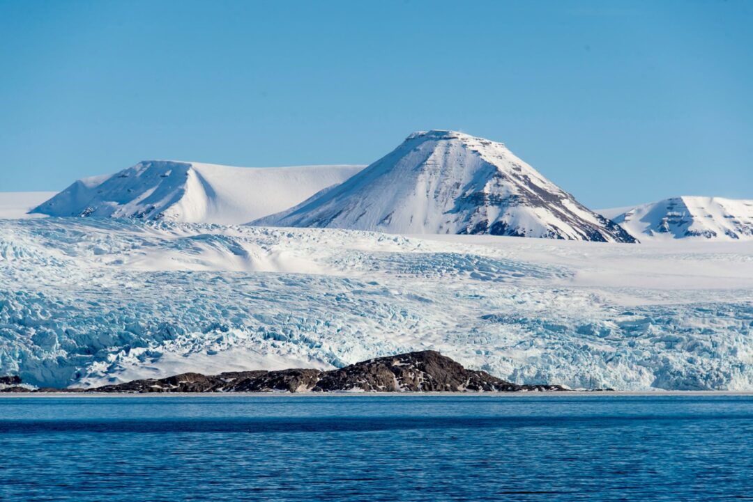 Icy fjord with snow-covered mountains and glacier in the distance